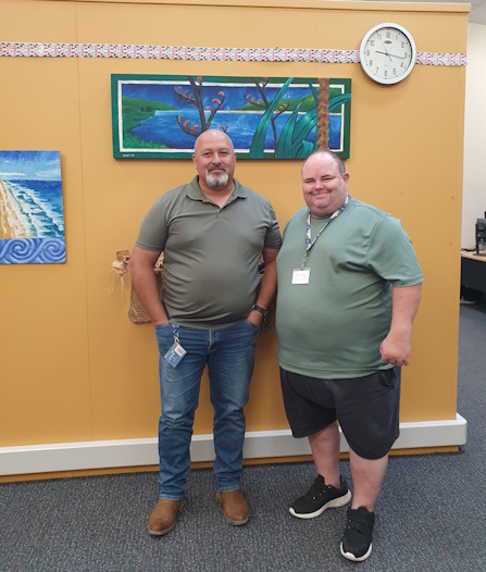 Howard League Driving Instructor Shane Clarkson and Probation Officer Justin stand against an orange wall at Kaitaia Community Corrections.