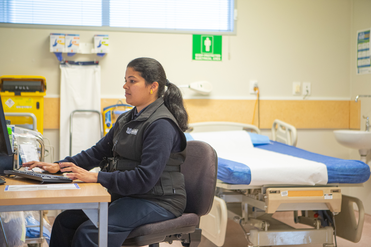 Nurse sits at computer in healthcare centre 